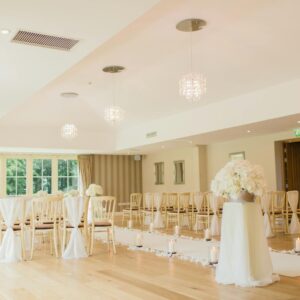 Brightly lit indoor wedding venue with elegant seating and floral decor, perfect for luxurious ceremonies.