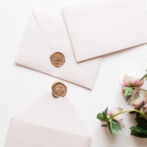 Minimalist arrangement of elegant envelopes with wax seals and flowers, perfect for invites.