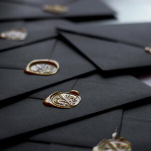 Close-up of stylish black envelopes featuring vintage wax seals, perfect for luxury invitations.