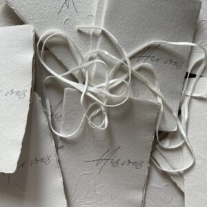 Top view of handcrafted invitations with ribbons on textured paper, perfect for weddings and events.