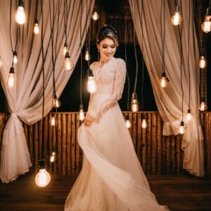 A stunning bridal photoshoot featuring a model in a white gown surrounded by hanging lights and curtains.