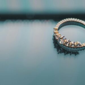 Close-up of a gold ring with diamonds on a reflective surface, showcasing elegance and luxury.